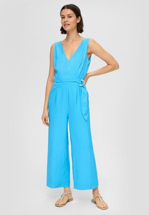 Blauer ärmelloser Jumpsuit mit einem tiefen V-Ausschnitt, tailliertem Bund und weitem Bein. Mit einem Stoffgürtel und einem runden Accessoire.