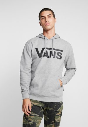 Sudadera gris con gran logo negro de "VANS", capucha con cordón, bolsillo canguro frontal y puños acanalados; combinada con pantalones cargo de camuflaje.