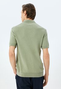 Olivgrön, kortärmad polo tröja med vertikal ribbning, klassisk krage och en bekväm passform med rak fåll.