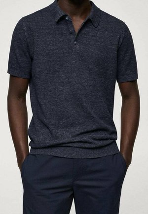 Polo à manches courtes bleu marine avec un tricot texturé, une patte à trois boutons et un col classique, porté avec un pantalon bleu marine foncé.