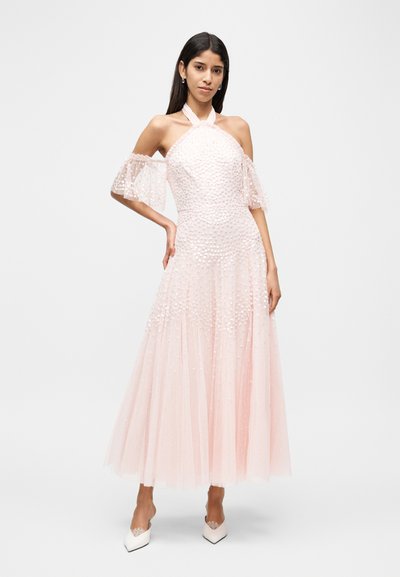 Ρόζ φόρεμα από τούλι με εφαρμοστό κορσέ, μανίκια τύπου "off-the-shoulder" και υφή από παγιέτες. Η φούστα ρέει και καταλήγει στη μέση της γάμπας. Λευκά ψηλοτάκουνα παπούτσια με μυτερή μύτη.