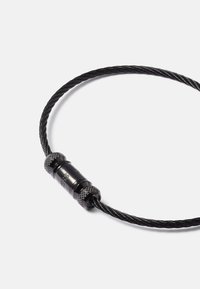 Cabo preto com um design torcido, apresentando um conector cilíndrico com pegadores texturizados e marcação em relevo perto do centro.