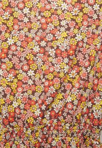 Tecido com estampado floral em tons de castanho, com flores vermelhas, cor-de-rosa, amarelas e brancas. Apresenta cintura elástica franzida e pequenos desenhos florais variados.