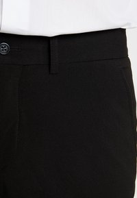 Svarta byxor gjorda av vävt tyg, med en traditionell knappstängning, slät front och sidofickor med en mjuk textur.