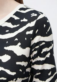 Mustvalge triibuline pikkade varrukatega särk soonikkoes. Omaduseks julged tiigrihõngulised mustrid, ümarsuur kaelus ja peen tekstuuriline detail.