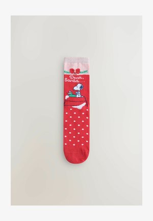 Calzino rosso con pois bianchi, risvolto rosa e un design di un cane e un regalo con il testo "Caro Babbo Natale." Il materiale sembra morbido e elastico.