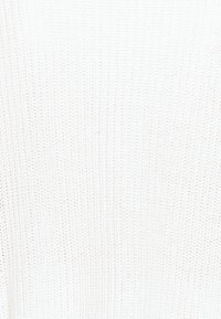 Tissu en tricot blanc texturé avec un motif côtelé fin, présentant un matériau léger et respirant adapté à divers vêtements.
