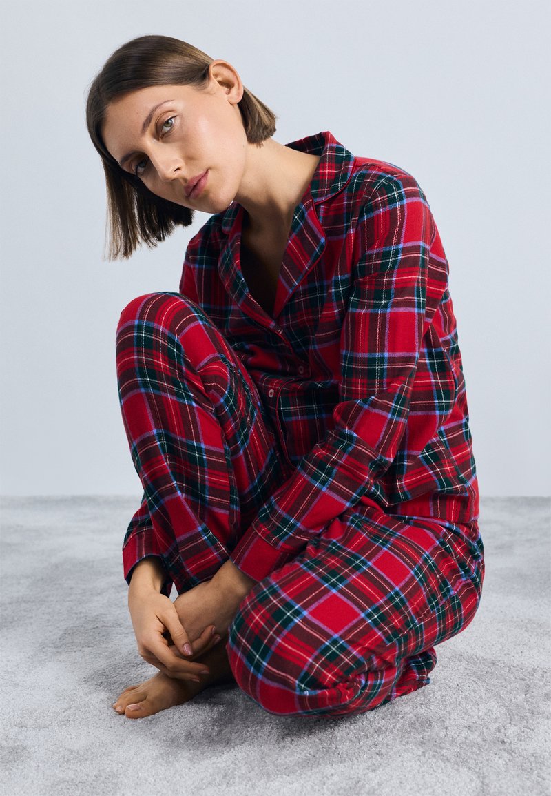 Rød og grønn rutete pysjamassett i myk stoff, med en knappetopp og elastisk livbukse, med oppbrettede ermer og en avslappet passform.