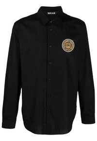 Maglietta nera a maniche lunghe realizzata in tessuto liscio, con una toppa del logo raffigurante un leone in oro e bianco nella zona sinistra del petto.