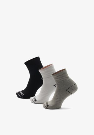 Knöchelsocken in Schwarz, Weiß und Grau. Rippstrickstruktur, verstärkte Ferse und Logoaufdruck an der Spitze. Jede Socke hat eine andere Farbe.