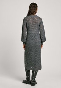 Robe en tricot grise avec un motif en dentelle en losanges, manches longues, et longueur mi-mollet. Finitions avec des poignets côtelés et un col rond.
