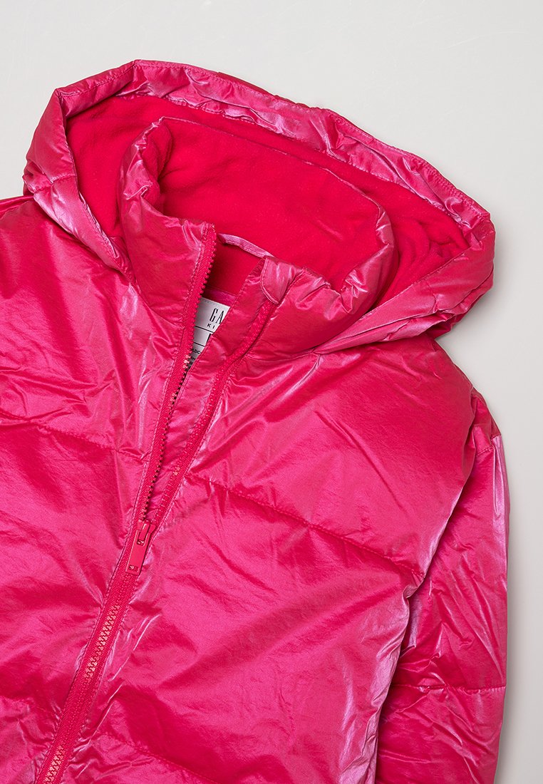 Veste matelassée rose avec une finition brillante, dotée d'une capuche et d'une fermeture éclair à l'avant. L'intérieur est en tissu rose uni contrastant.