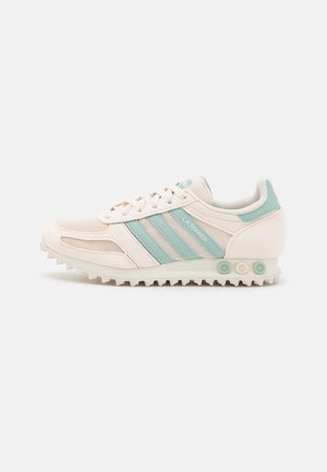 Hvid og lyseblå Adidas LA Trainer sneaker med mesh og ruskind overdel, snørelukning foran og tekstureret gummisål med runde nitter.