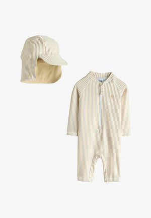 Stribet beige og creme sol-dragt med lange ærmer og lynlås, kombineret med en matchende kasket med øreklapper og skygge.