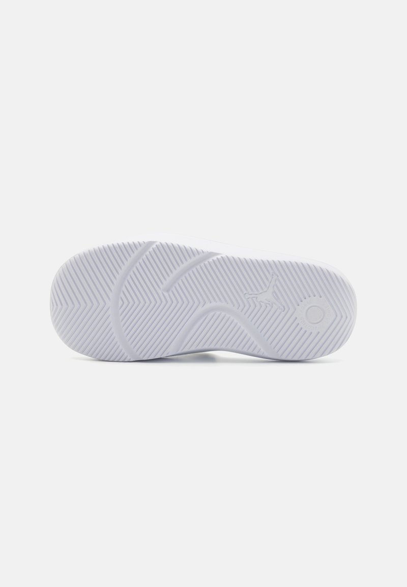 Weiße Sportschuhsohle mit einem strukturierten, wellenförmigen Muster und multidirektionalen Rillen für Halt. Rundes Logo an der Seite.