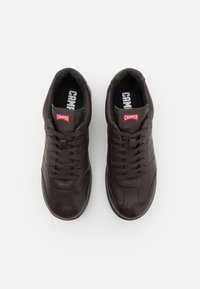 Sneaker in pelle marrone con punta arrotondata, accenti laterali testurizzati e lacci piatti. La soletta presenta un logo del marchio visibile.