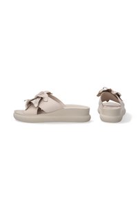 Beige schuifsandalen met een strikaccent, voorzien van een soepele leren bovenkant, een gestructureerde zool en een lage wig hiel voor ondersteuning.