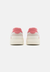 Sneaker bianchi e grigio chiaro con dettagli in suede rosa, un tallone testurizzato e una suola bianca spessa, visti da dietro.