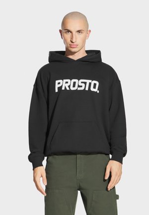 Czarna bluza z kapturem z dużym białym napisem „PROSTO.”, z przednią kieszenią i sznurkiem przy kapturze. Tkanina wydaje się miękka i teksturowana.