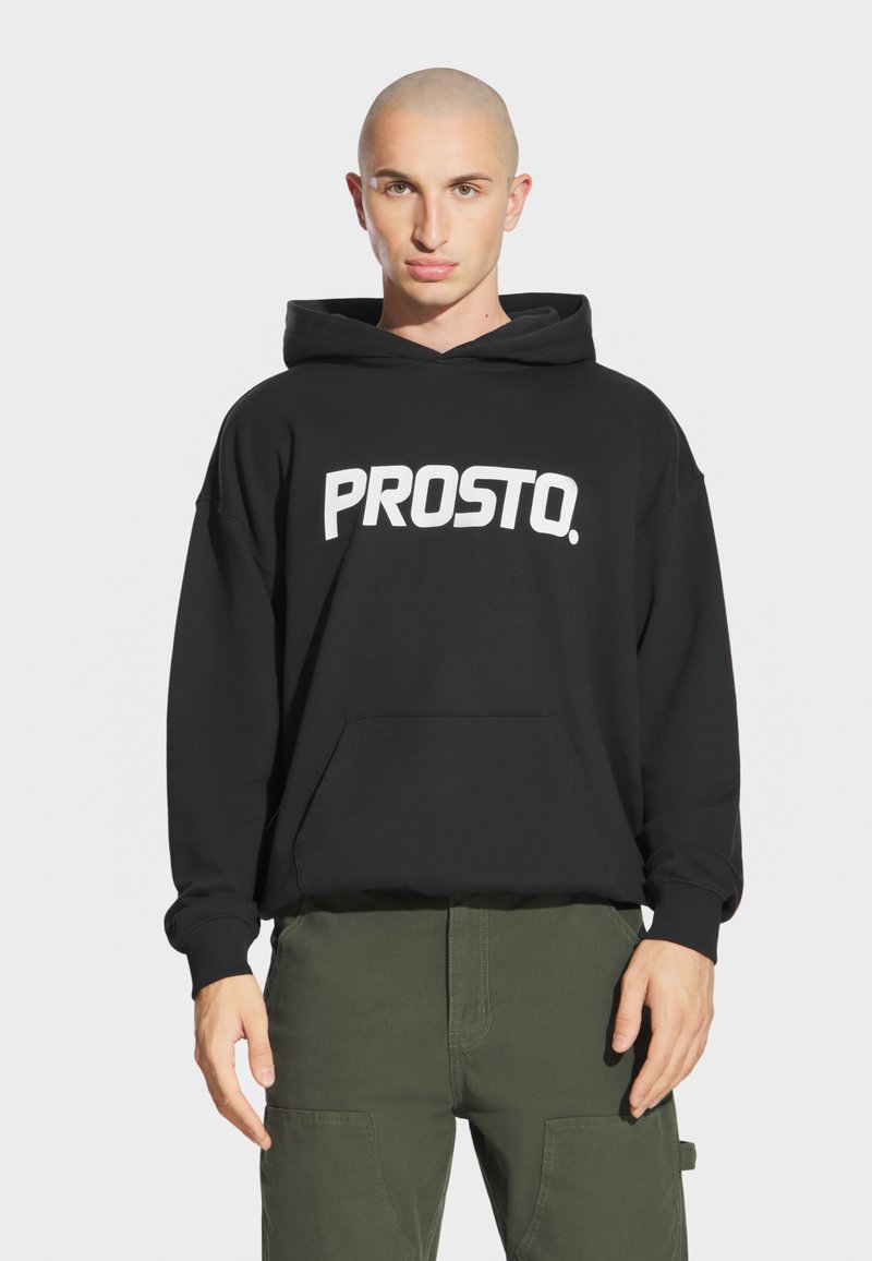 Czarna bluza z kapturem z dużym białym napisem „PROSTO.”, z przednią kieszenią i sznurkiem przy kapturze. Tkanina wydaje się miękka i teksturowana.