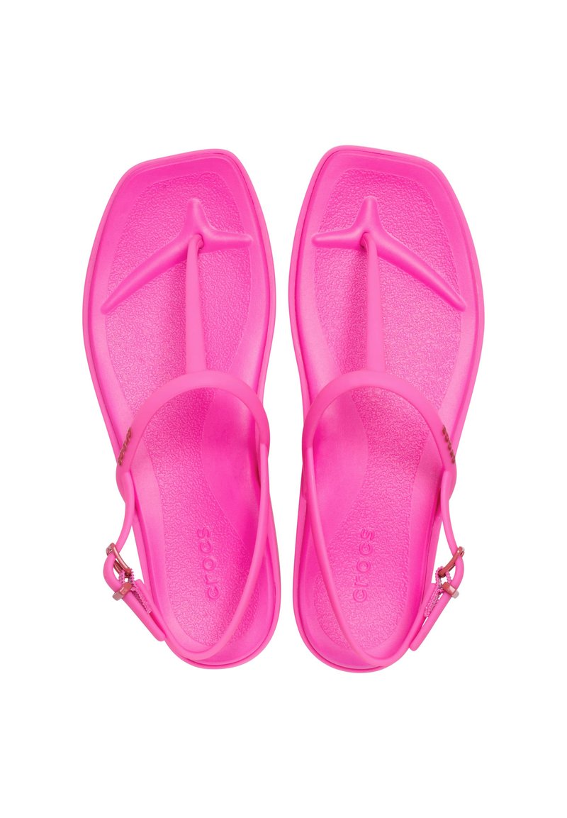 Różowe, plastikowe sandały z paskiem w między palcami i z paskiem wokół kostki. Teksturowana wkładka dla lepszego uchwytu i komfortu. Brak wyraźnych wzorów lub elementów ozdobnych.
