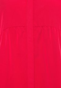 Abito rosso con una texture liscia, dotato di dettagli plissettati intorno alla vita e una cucitura centrale. Design semplice senza ulteriori motivi o accenti.