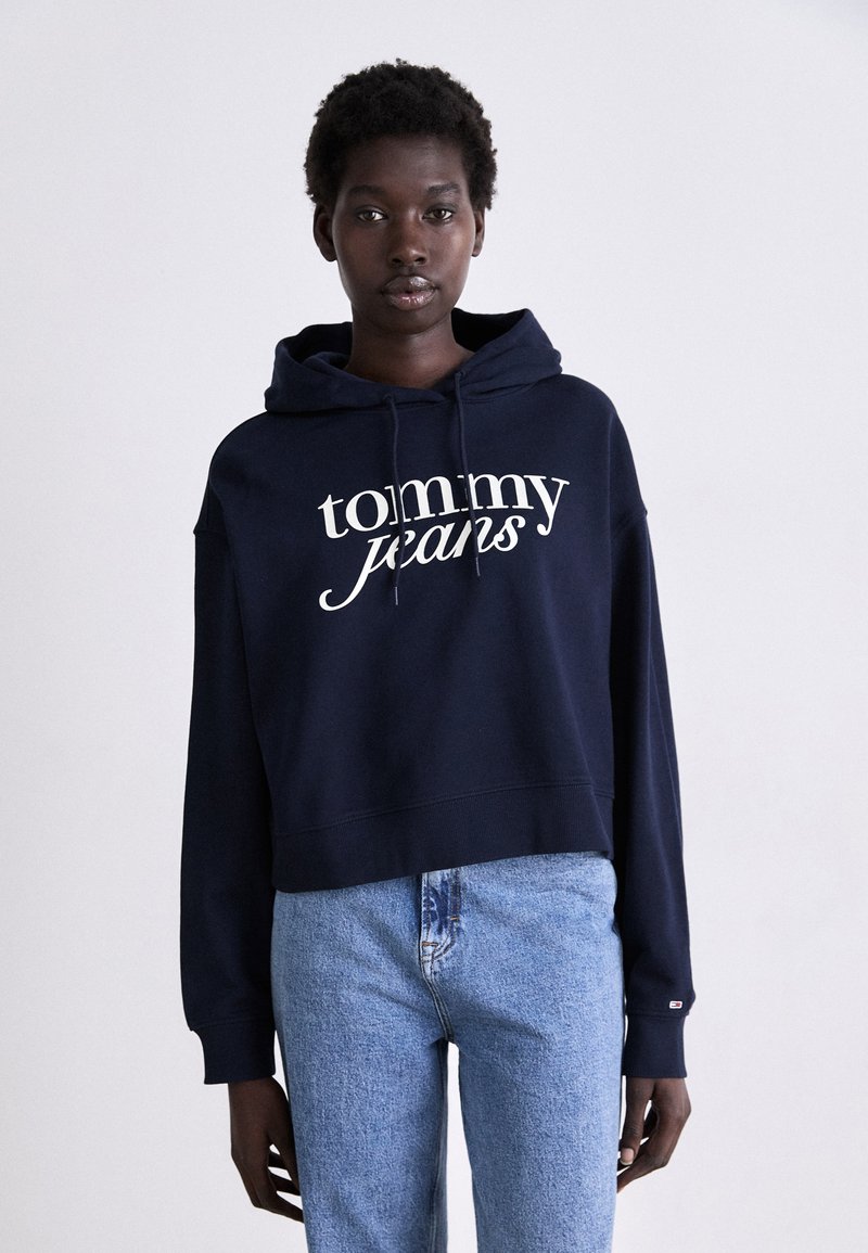 Hoodie cropped blu navy in cotone, con stampa bianca del logo "tommy jeans" sul davanti e cordini sul cappuccio.