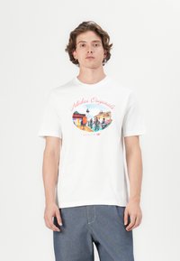 Balta medvilnė marškinėliai su spalvinga grafiką, kurioje yra užrašai "Adidas Originals" ir "Berlynas", trumpomis rankovėmis ir apvaliu kaklu.