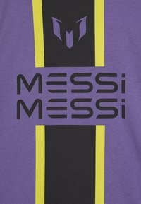 Violetinis marškinėlis su juodais ir geltonais vertikaliais dryžiais. Drąsus juodas tekstas „MESSI“ du kartus, viršuje yra stilizuotas logotipas.