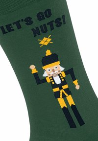 Zielona skarpetka z wzorem krakena w kolorach żółtym, czarnym i białym, a powyżej tekst "ROZKRĘCAMY TO!" oraz dekoracyjne akcenty.