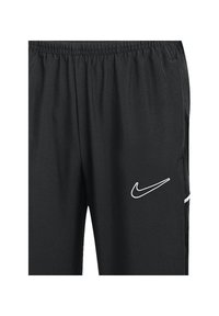 Pantalons de sport noirs en tissu léger, avec une taille élastique et un logo Nike blanc sur le côté gauche.