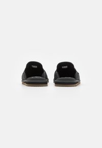 Sorte loafers i teksturert stoffoberflate, avrundet bakdel og gummisåle. Viser et rent design og minimal innvendig fôr.