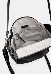 Borsa a mano in pelle nera con interno in tessuto grigio, dotata di chiusura con cerniera, tasca interna e tracolla regolabile.