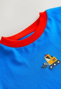 Blue cotton t-shirt with a red ribbed collar. Features an embroidered yellow excavator design with gray accents and a red light on top.