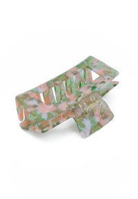 Hårklämmor i genomskinlig plast med blommönster i grönt, rosa och vitt; har en central fjädrmekanism och breda klor.