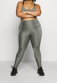 Szare legginsy sportowe o teksturowanym wykończeniu, z wysokim stanem i detalami w postaci paneli. Połączone z dopasowanym stanikiem sportowym i czarnymi trampkami.