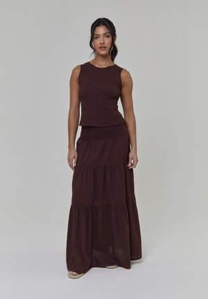 Braunes, gestricktes Tanktop mit rohen Kanten, kombiniert mit einem mehrstufigen, fließenden Maxirock. Glatte Textur mit einem dezenten Muster, bietet eine lockere Passform.