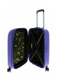Valise rigide violette avec deux roues, dotée d'un intérieur noir orné d'icônes jaunes et d'une sangle de sécurité.