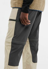 Cargo-broeken met een twee-kleurig ontwerp in donkergrijs en beige, voorzien van een ritssluiting zak, gemaakt van lichtgewicht, gestructureerde stof.