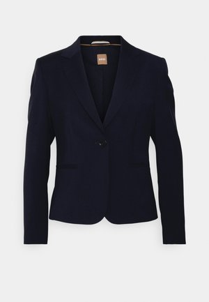 Blazer bleu marine avec un design ajusté, fermeture à un bouton, revers crantés et deux poches avant. Fabriqué à partir d'un tissu lisse et structuré.