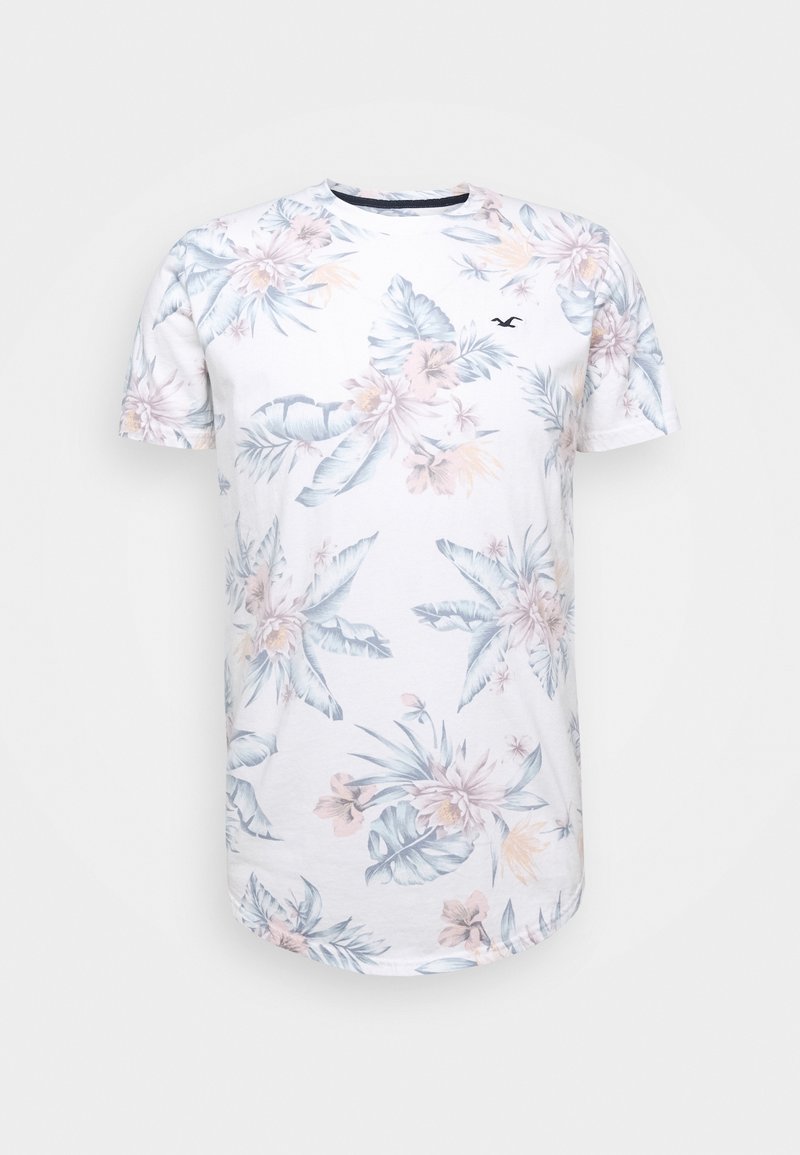 Vit bomulls-T-shirt med en ljusblå och pink tropisk blommönster, rund hals och korta ärmar. Diskret varumärkeslogo på bröstet.