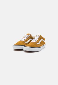 Serge skate sko i sennepsgult med hvite snører. Har en svart gummisåle og et karakteristisk hvitt swoosh-detall på siden.
