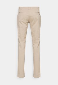 Béžové bavlněné kalhoty s rovnými nohavicemi, které mají dvě zadní kapsy a minimální zdobení. Hladká textura s čistým zakončením.