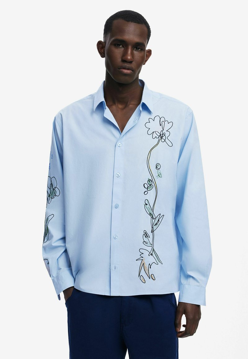 Light blue long-sleeve shirt featuring floral embroidery in black and green outlines along the left side, button-up front, and relaxed fit.