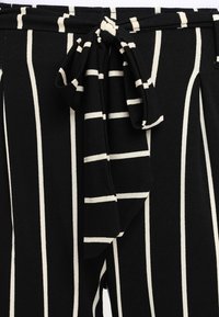 Zwart-witte gestreepte stof met een zachte textuur heeft een gestrikte taille detail, wat een gestructureerde, vloeiende silhoeet creëert.
