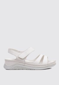 Sanda blanca con puntera cerrada y dos correas de velcro ajustables. Parte superior de sintético con una suela texturizada para mayor agarre y comodidad.