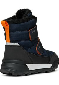Bota de invierno azul marino con suela de goma negra, parte superior de tejido texturizado, detalles en color naranja y dos correas ajustables de Velcro. Forro de forro polar cerca del tobillo.