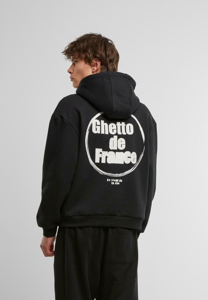 Black hoodie featuring a round graphic print on the back with the text “Ghetto de France.” Soft fabric, relaxed fit, with a front pocket.