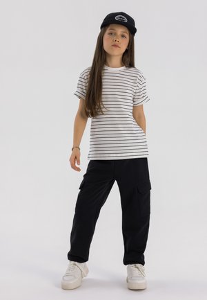 White and black striped t-shirt, black cargo pants with pockets, white sneakers, and a black cap. Simple, casual outfit design.