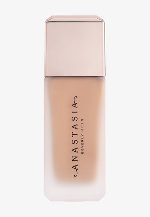 Flacon rectangulaire en verre dépoli avec fond de teint liquide beige et bouchon carré métallique portant l'étiquette « Anastasia Beverly Hills ».